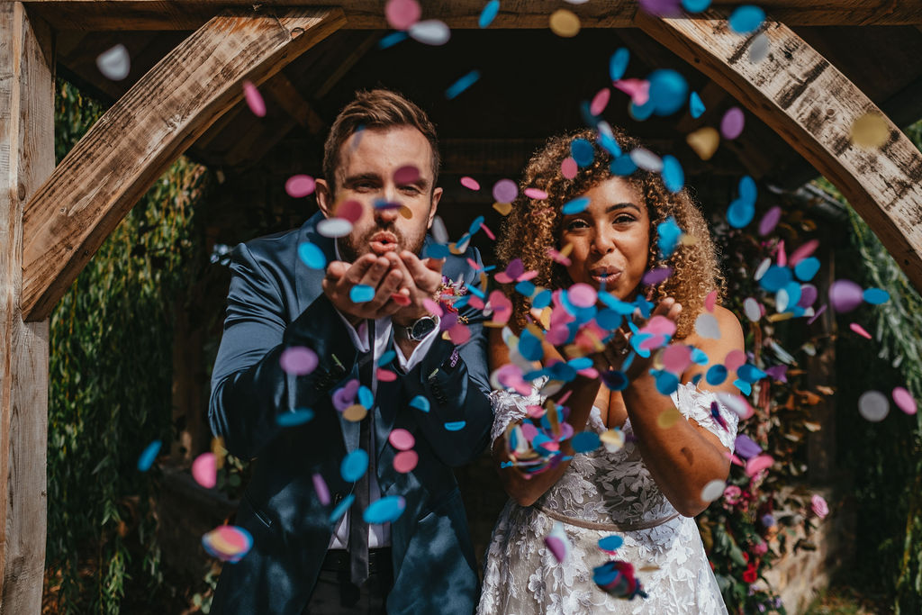 Couple blowing Colourful Confetti at Skipbridge Country Weddings, Yorkshire | Mirl & Co Photo