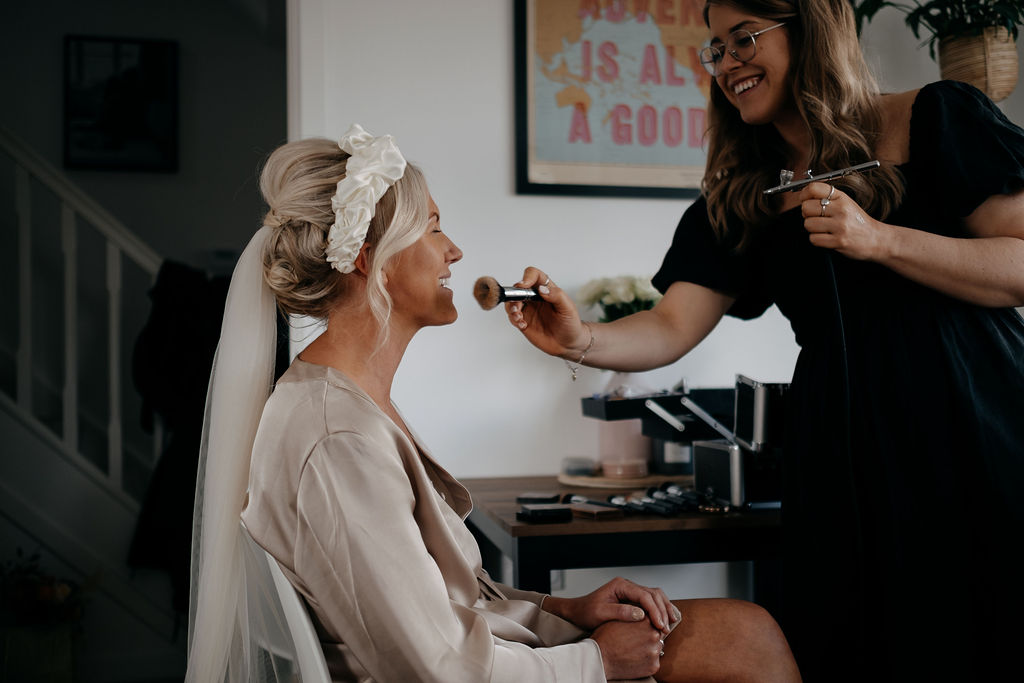Bride getting her makeup done at home before the wedding