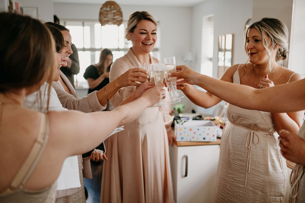 bridesmaid making a toast with prosecco in the kitchen