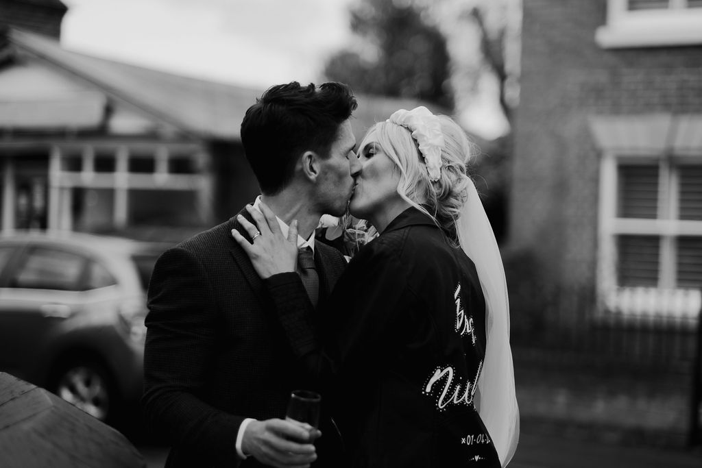 blck and white image of newly weds kissing in a leather jacket at an Amalfi White Wedding